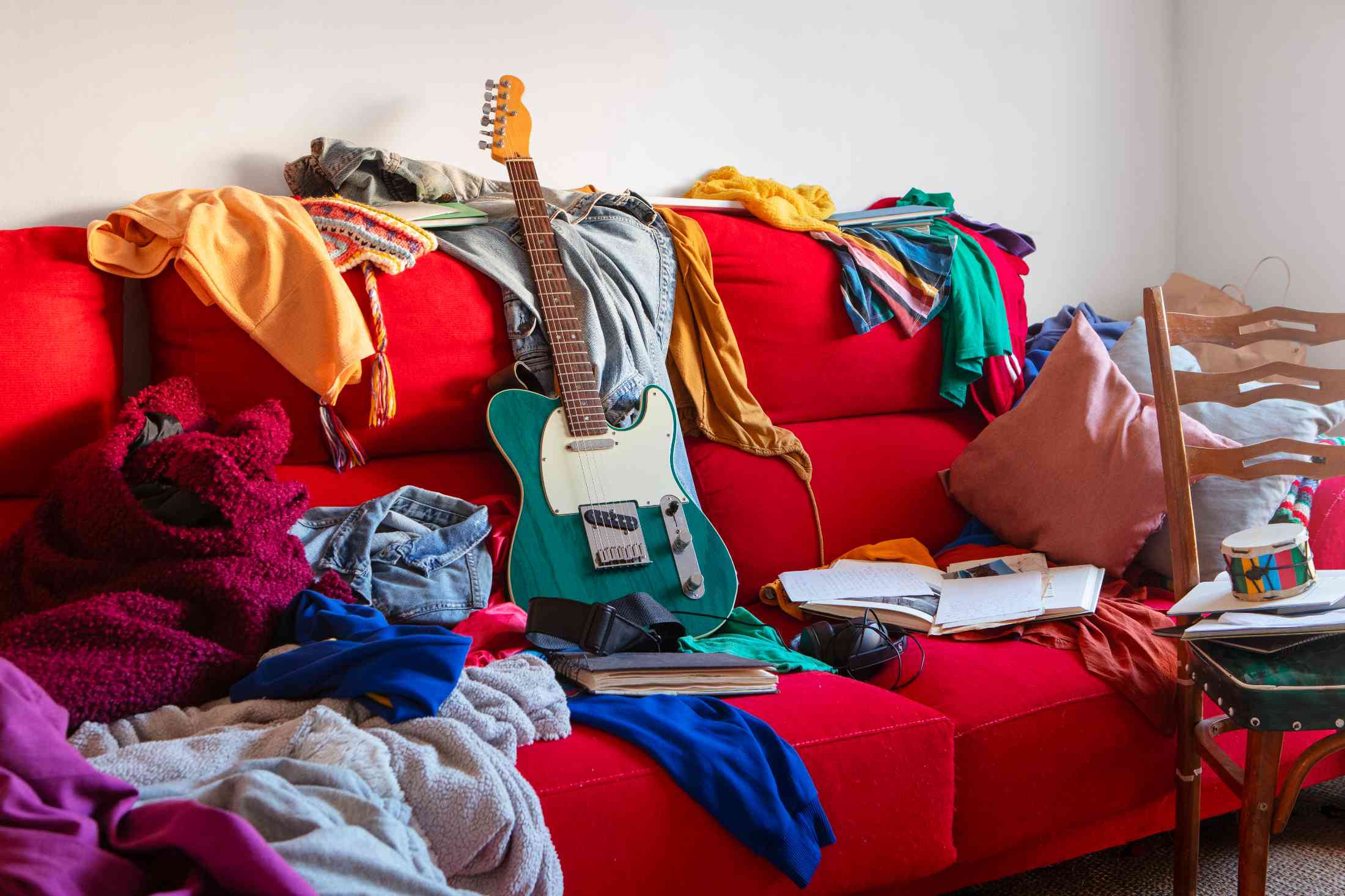 rotes Sofa voll mit Klamotten